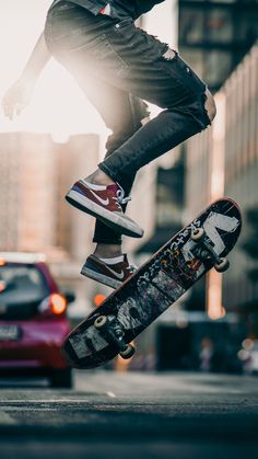 a skateboarder doing a trick in the air over a street with cars behind him