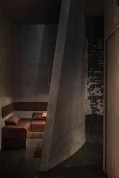 an empty room with some brown couches on the floor and a wall in the background