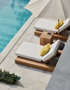 two lounge chairs and an umbrella next to a pool