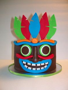 a cake decorated like a mask with feathers on top