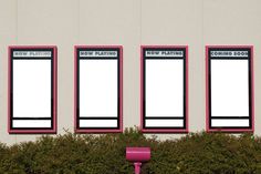 three pink chairs sitting in front of a white building with black and red signs on it