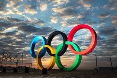 the olympic rings are lit up in front of an evening sky with clouds above them