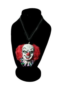 a necklace with a clown face on it and a red wig hanging from the neck