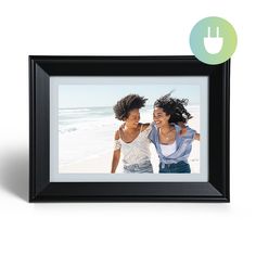 two women standing next to each other in front of a black frame with the word love on it