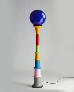 a multicolored table lamp sitting on top of a white floor next to a gray wall