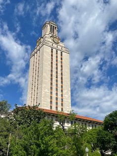 a tall white building with a clock on the top and trees around it's sides