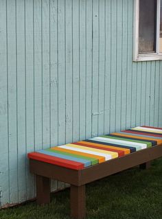 a colorful bench sitting in front of a blue building with a white door and window