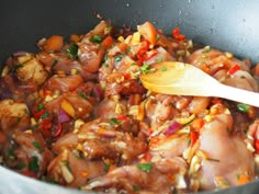 chicken and vegetables cooking in a pan with a wooden spoon