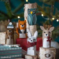 several small wooden animals sitting on top of birch logs in front of a christmas tree