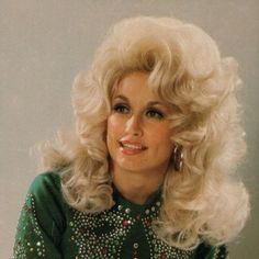 an old photo of a woman with blonde hair wearing a green shirt and earrings on her head