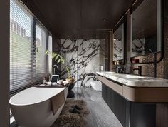 a bathroom with marble walls and flooring next to a bathtub in front of a window