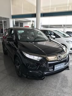 a black honda hr - v is parked in a car showroom with other cars