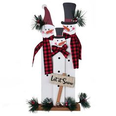 two snowmen standing next to each other on top of a wooden sign that says let it snow