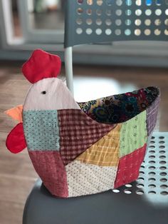 a small patchwork chicken sitting on top of a chair