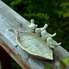 three ceramic rabbits sitting on top of a leaf