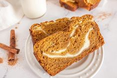 slices of pumpkin bread on plates next to cinnamon sticks and a glass of milk in the background