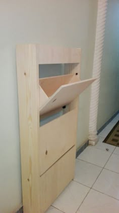 a wooden shelf with an open drawer on the top and bottom, next to a tiled floor