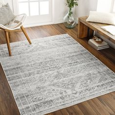 a living room area with wooden floors and white rugs on the hardwood flooring