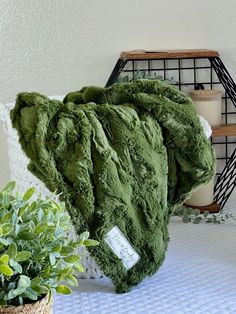 a pile of green blankets sitting on top of a bed next to a potted plant