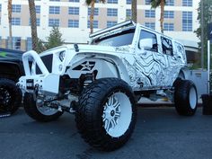 a white jeep parked in front of a tall building with palm trees on the side