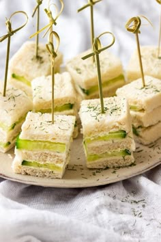 small sandwiches are arranged on a plate with toothpicks sticking out of the top