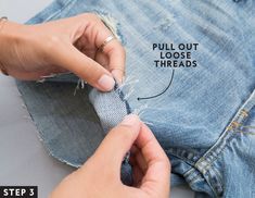 someone is cutting through the hole in their jean pants with a pair of scissors and thread