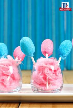 pink and blue cake pops in small glass vases on a tray with wooden table