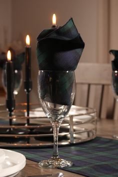 a table set with wine glasses, plates and candles