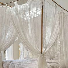 a canopy bed with white bedspreads and curtains