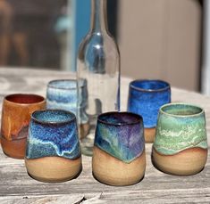 five different colored cups sitting on top of a wooden table