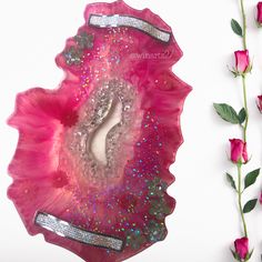 a pink flower with some glitter on it next to a piece of art that looks like an agate shell