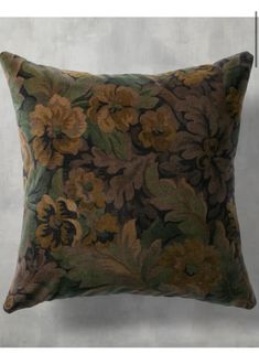 a brown and green floral pillow sitting on top of a white wall