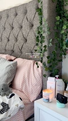 a bed that has some plants growing on the headboard and pillows in front of it