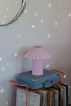 a pink lamp sitting on top of a blue suitcase