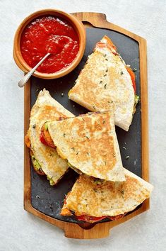 two quesadillas cut in half on a plate with salsa and ketchup