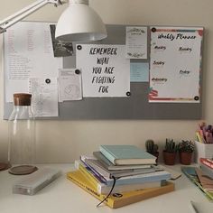 a white desk topped with books next to a lamp and other office supplies on top of it