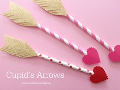 three heart shaped straws with paper straw tops on a pink surface next to hearts