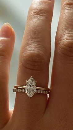 a woman's hand with a diamond ring on top of her finger and an engagement band