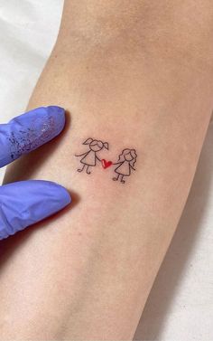 a woman's arm with a small tattoo on it that has two people holding a heart