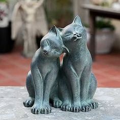 two cats sitting next to each other on top of a cement slab in front of a house