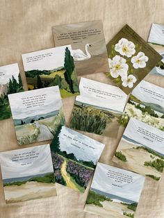 several cards with white flowers and watercolors are on a tablecloth next to each other