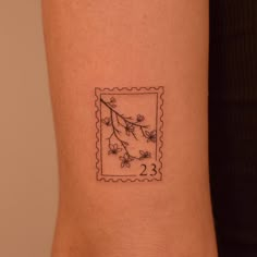 a small tattoo on the arm of a woman's left arm with flowers and leaves