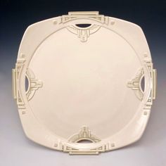 a white plate with an intricate design on the front and sides, set against a gray background