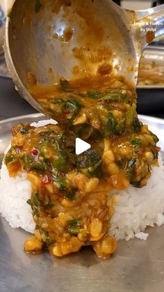 a silver plate topped with rice covered in sauce next to a metal pan filled with food