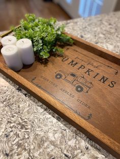 two candles are sitting on top of a wooden sign that says pumpkins and some herbs