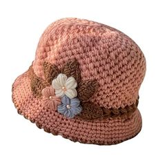 a pink crocheted hat with flowers on the brim and brown ribbon around the brim