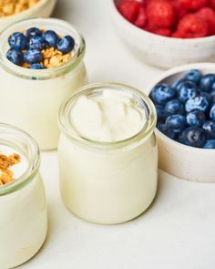 three jars filled with yogurt, granola and blueberries on a table