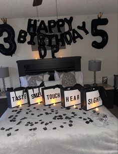 a bedroom decorated with black and white decorations, candles and birthday signs on the bed