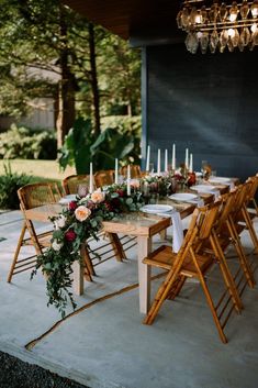 a long table with candles and flowers on it is set up for an outdoor dinner