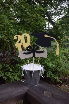 a graduation cake topper sitting on top of a bucket filled with white frosting